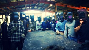 Interns pose for a picture with their welding masks on in the workshop before learning how to weld. Photo by Marcin Jakubowski